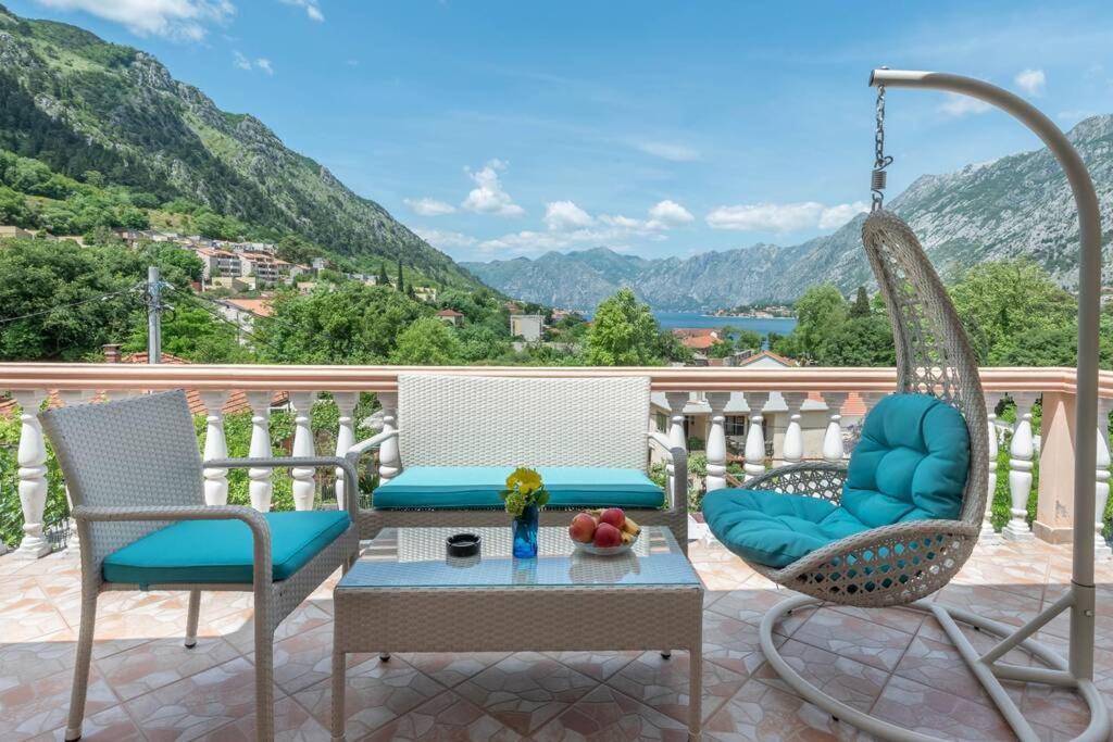 twee stoelen en een tafel op een balkon met bergen bij Apartment Vento di Bocche in Kotor