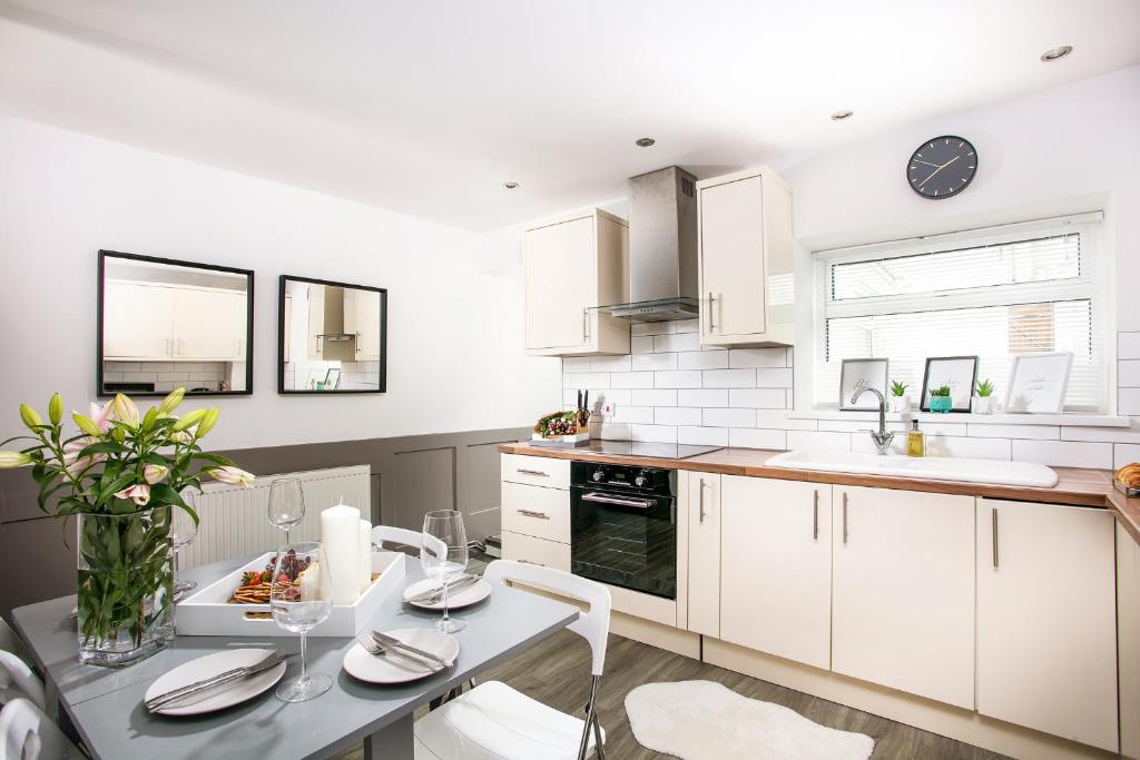 een keuken met witte kasten en een tafel met stoelen bij Bijoux Plymouth Cottage - Sleeps 6 - By Habita Property in Plymouth