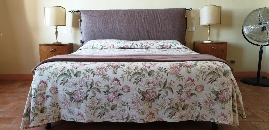a bedroom with a bed with a floral bedspread and two lamps at Ascanio Appartamenti in Castiglione del Lago