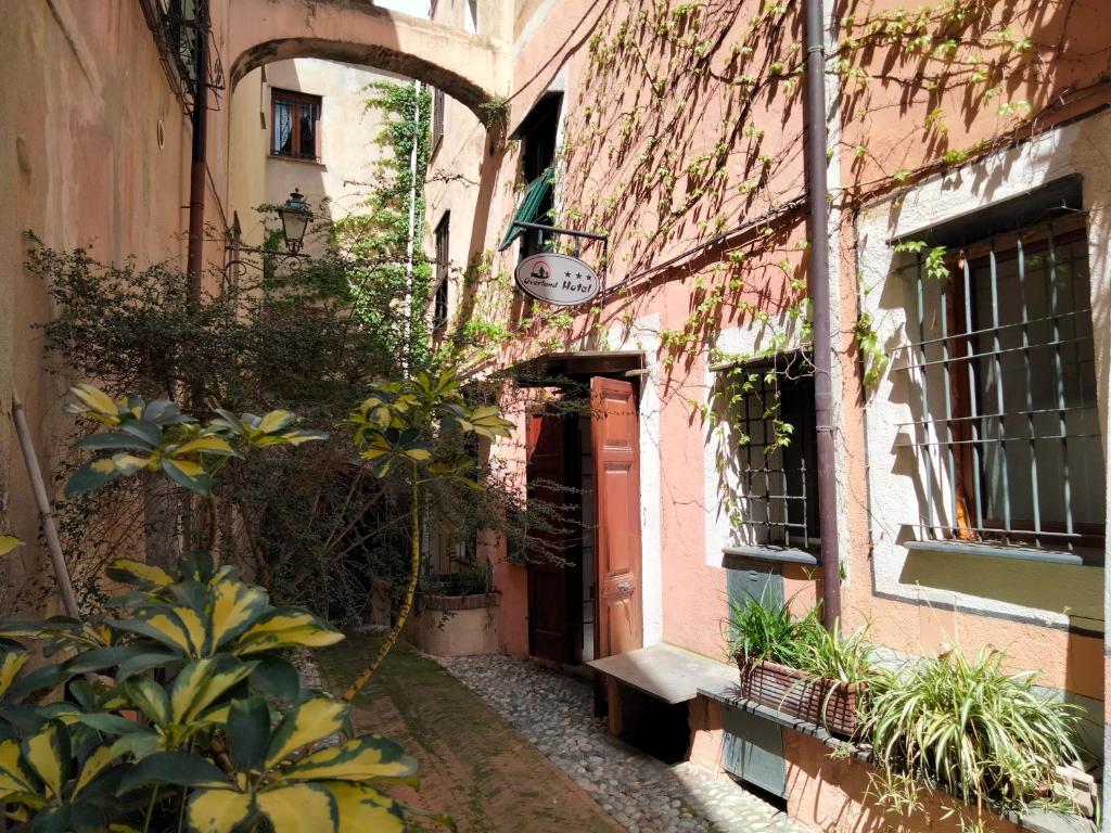 an alley in an old building with a red door at Hotel Overland in Toirano