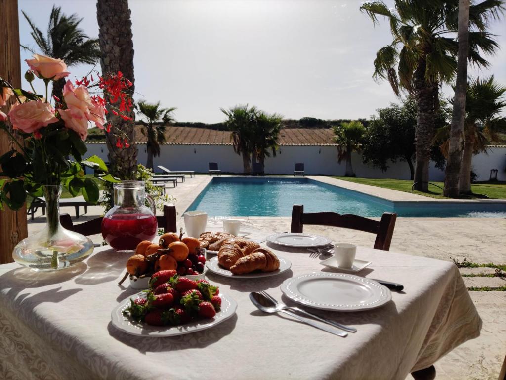 Partanna的住宿－Villa Alaya - Luxury Villa with private pool，一张桌子,上面有食物,放在游泳池边