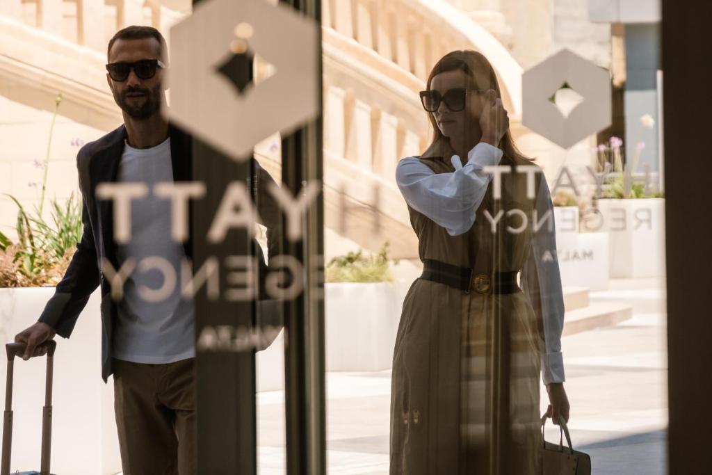 a man and a woman standing next to a sign at Hyatt Regency Malta in St. Julianʼs