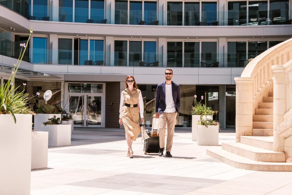 a man and woman walking in front of a building at Hyatt Regency Malta in St. Julianʼs