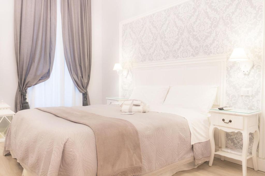 a white bedroom with a white bed and a white table at Charme & Chic Luxury in Rome