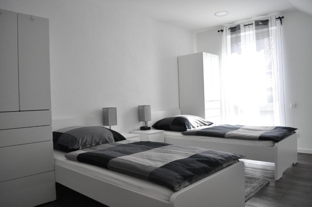 two beds in a bedroom with white walls at B Home SLEEP & WORK in Burgrieden