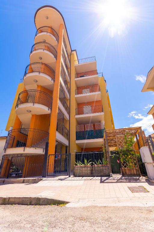 a yellow building with a fence in front of it at Residence Palazzo Sayonara in Tortoreto Lido