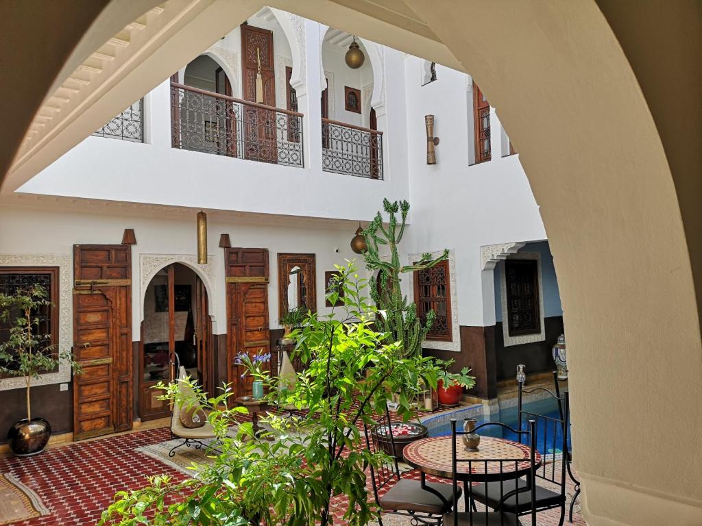 un patio con mesas y plantas en un edificio en Riad Charme d'Orient Adults Only, en Marrakech