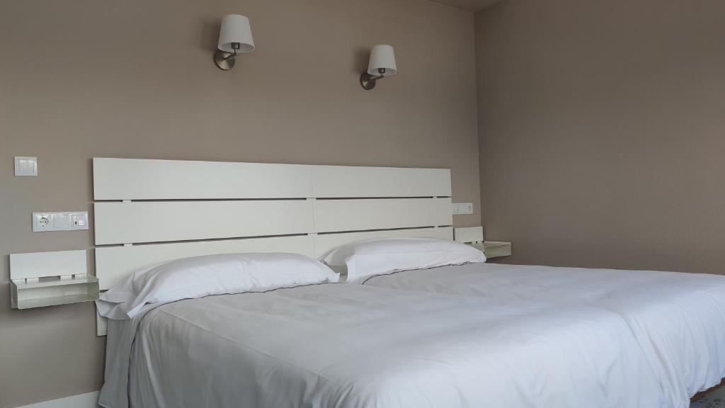 a bedroom with a large white bed with two pillows at Hotel Román in Naveces