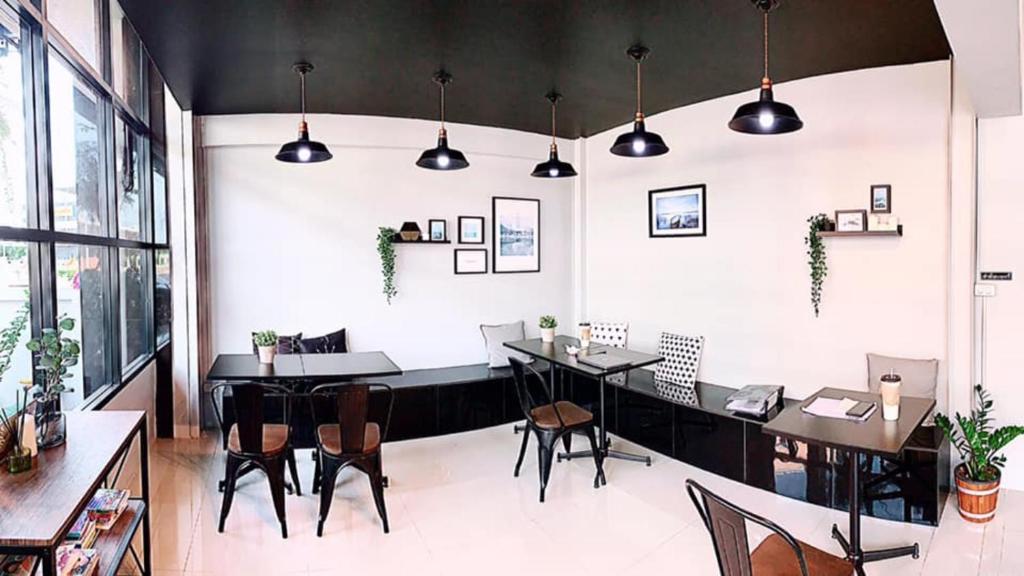 a dining room with tables and chairs and lights at Rest Point Sampran in Nakhon Pathom