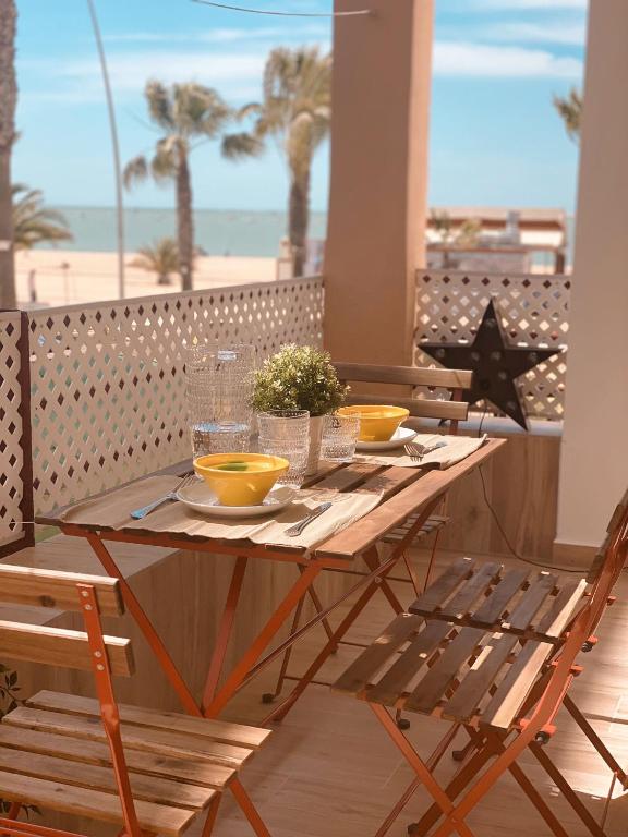 drewniany stół z żółtymi miskami na balkonie z plażą w obiekcie SibsSanlucar MARITIMO-1ª Linea de Playa w mieście Sanlúcar de Barrameda