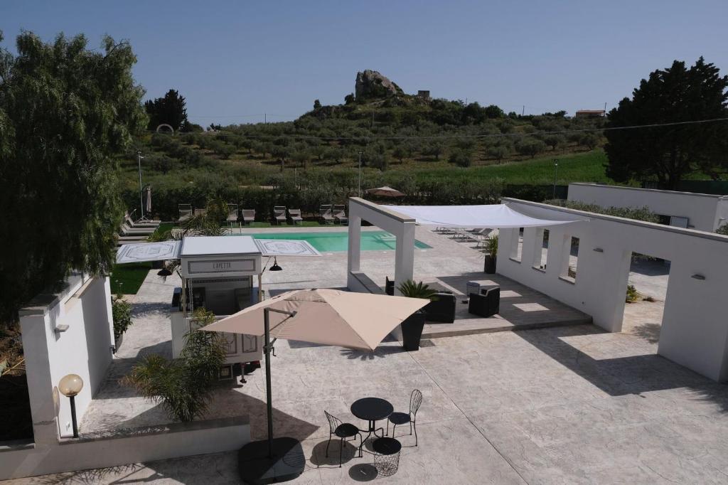 a patio with a pool and a table with an umbrella at Villa Valenza in Favara