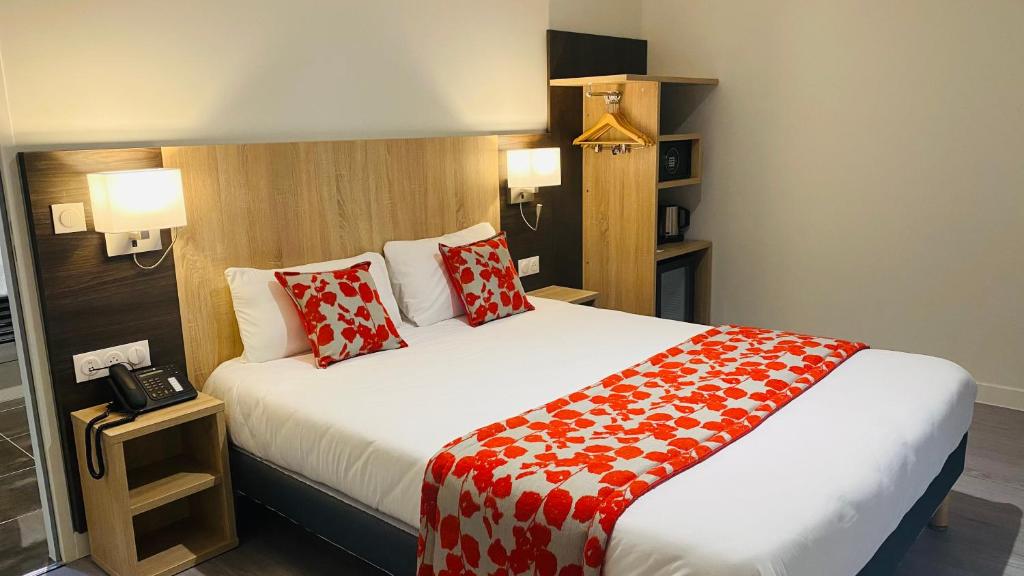 a hotel room with a large bed with red pillows at Hotel Martinez Grenay in Grenay