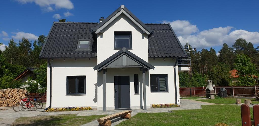 een wit huis met een zwart dak bij Mazury domek całoroczny przy lesie, jezioro in Pelnik