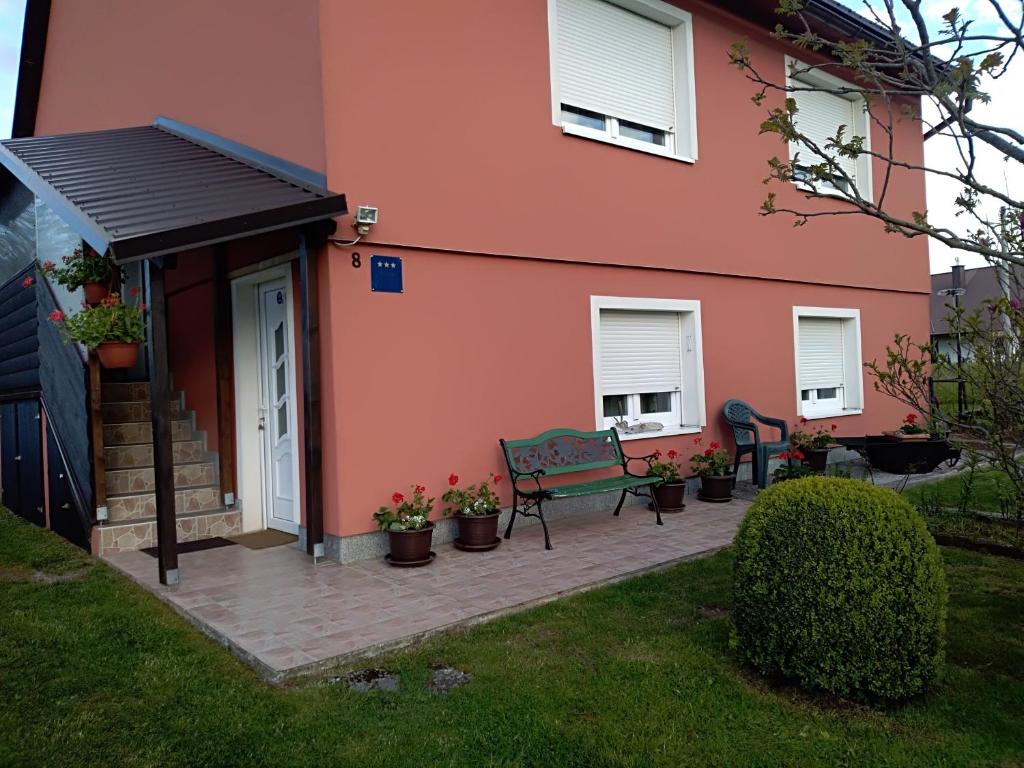 uma casa cor-de-rosa com um banco à frente. em Apartman Ris Gorski Kotar Crni Lug em Delnice