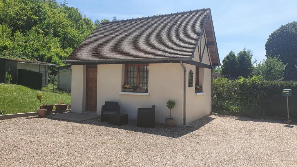 een klein wit huis met een raam en een plant bij Gîte L'EAU VIVE in Noyers