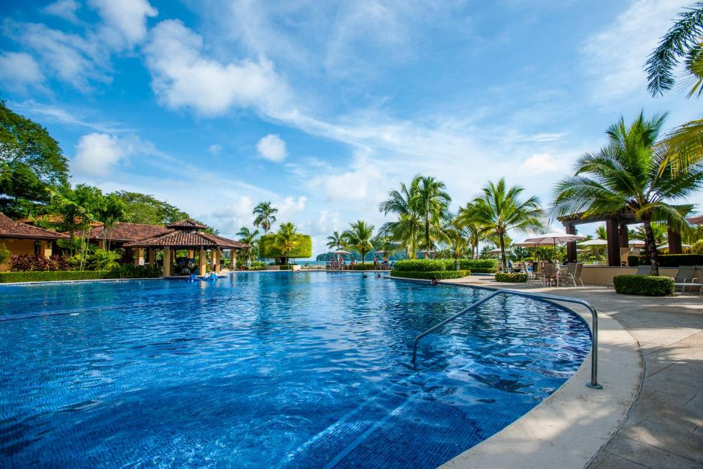 a swimming pool at a resort with palm trees at Stay In CR Los Sueños Condos in Jacó