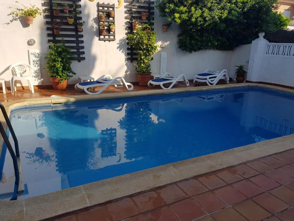 una piscina con 2 sillas de jardín frente a una casa en GRAN ADOSADO EN ZONA TRANQUILA CON PISCINA PRIVADA solo familias, en Gandía