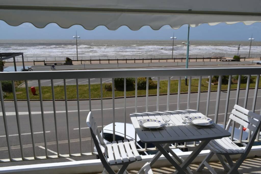 d'une table et de chaises sur un balcon donnant sur la plage. dans l'établissement Appartement studio vue mer les pieds dans l'eau, à Saint-Jean-de-Monts