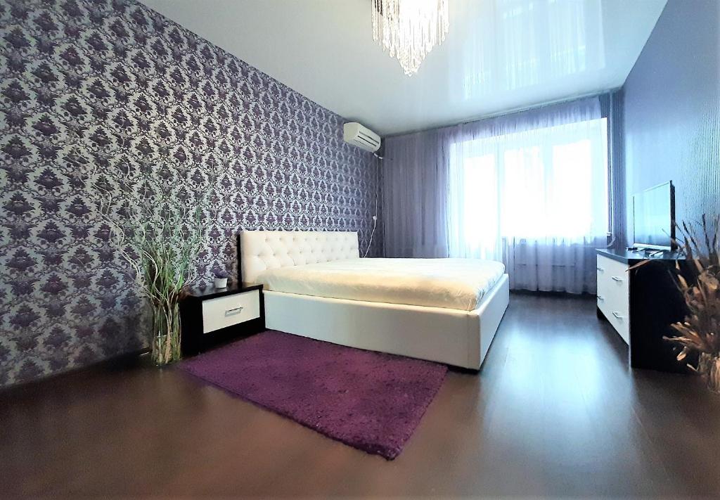 a bedroom with a bed and a purple accent wall at MEGAPOLIS улица Арсенальная 4-А-136 in Voronezh