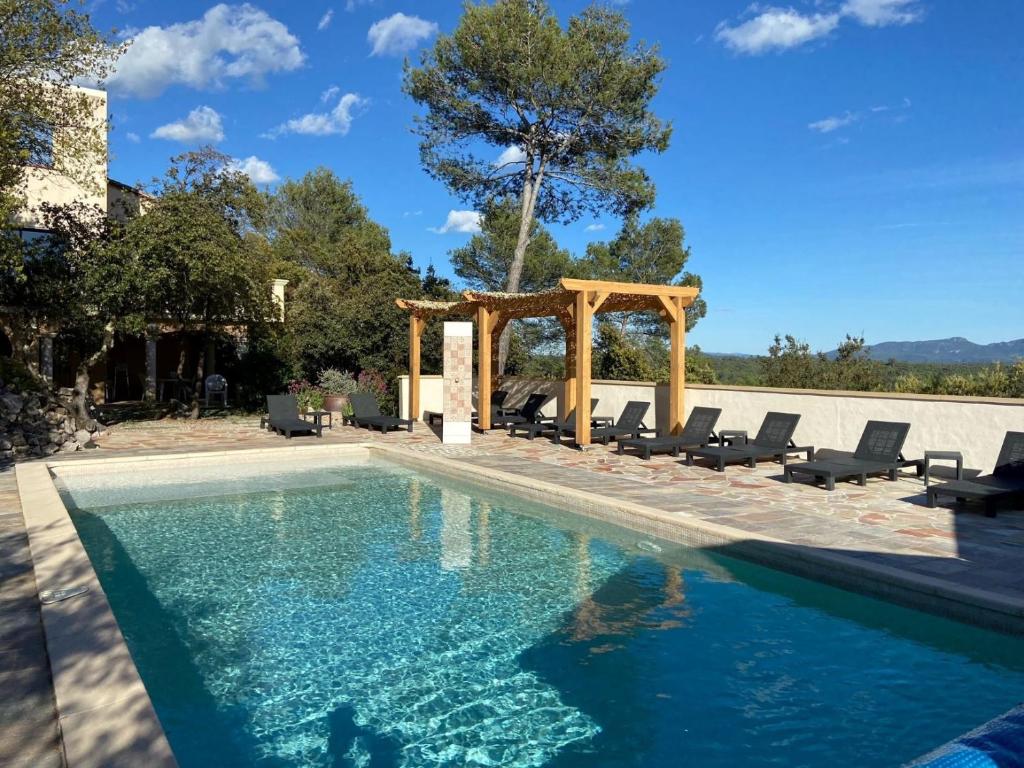 a swimming pool with a pergola and chairs around it at Villa Asunda B&B Spa & Sauna, Chambres d'Hôtes in Saint-Maximin-la-Sainte-Baume