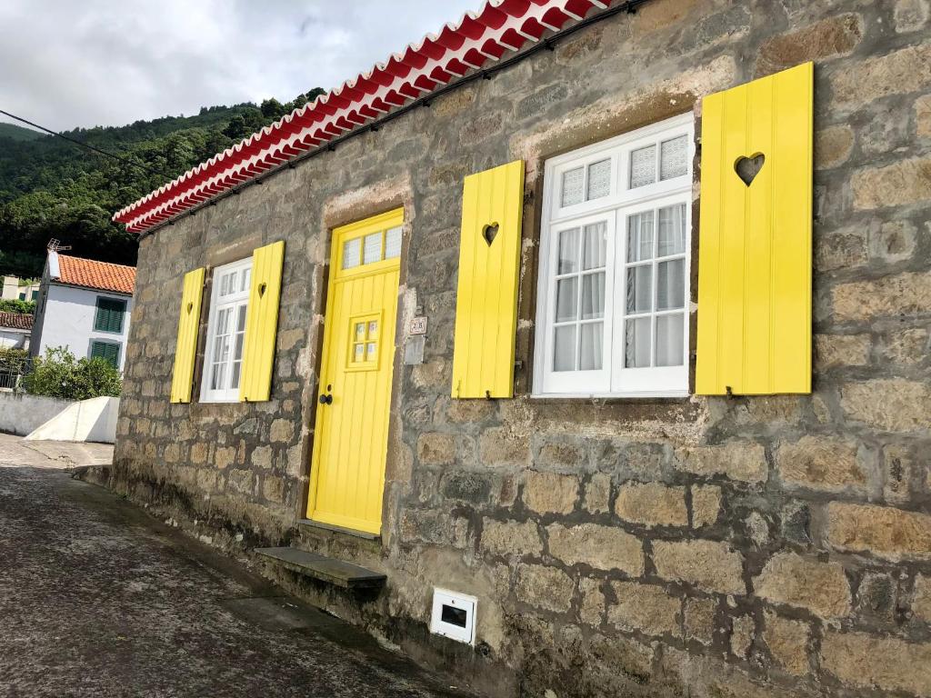 a stone building with yellow doors and windows at Casa Auri in Faial da Terra