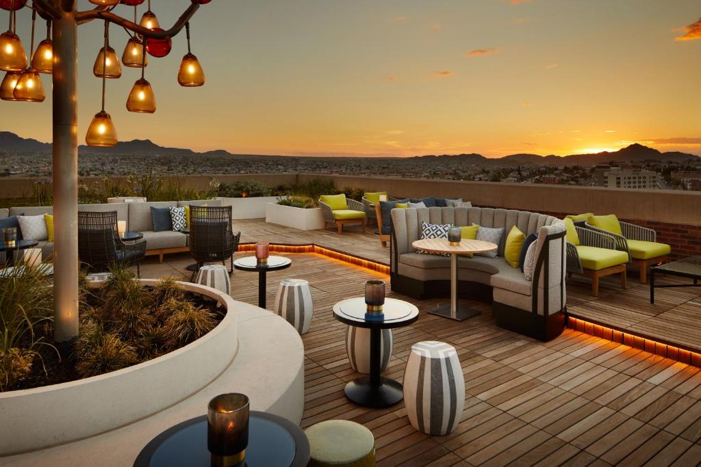 a rooftop patio with couches and tables and a sunset at The Plaza Hotel Pioneer Park in El Paso