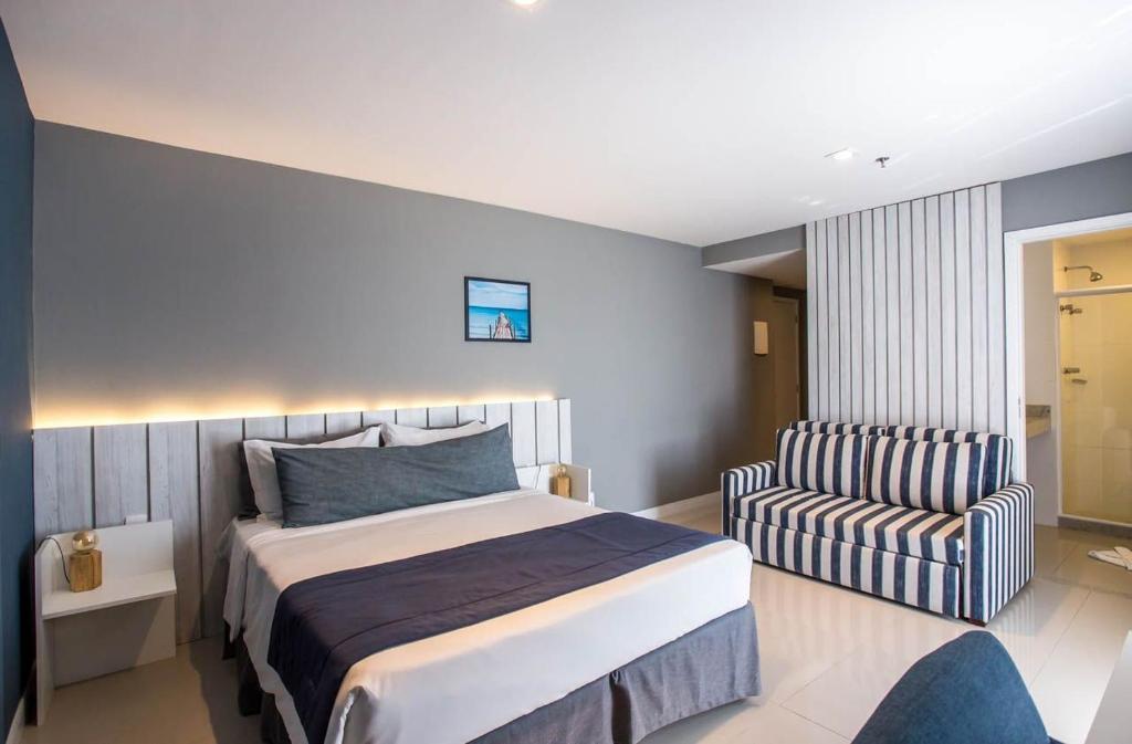 a hotel room with a bed and a chair at Flat 402 in Cabo Frio 700m from the beach in Cabo Frio