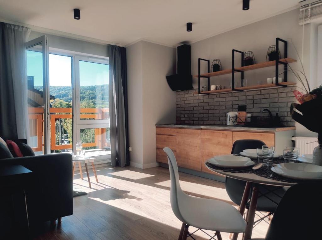 シュクラルスカ・ポレンバにあるApartament Dream Apart IIのリビングルーム(テーブル、椅子付)、バルコニーが備わります。