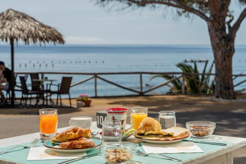 a table with plates of food and a view of the ocean at Hotel Ristorante La Conchiglia in Cala Gonone