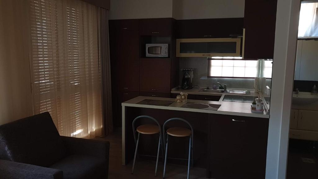 a kitchen with two bar stools next to a counter at Keller Arany Apartmanok in Hajdúszoboszló