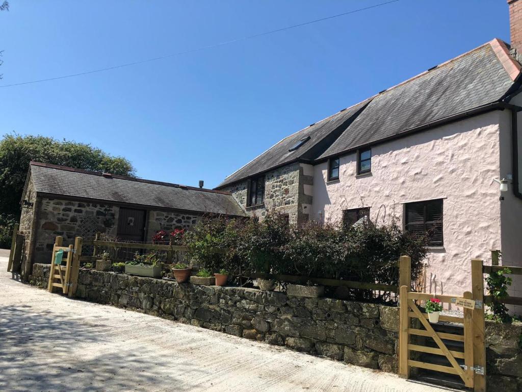 an old stone building with potted plants on a wall at Farm accommodation - The Lizard Peninsula, Cornwall in Helston