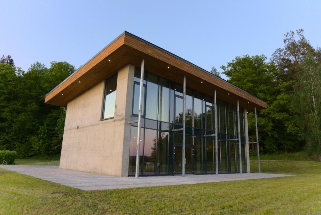 a building with large glass windows in a field at Brīvdienu māja Pakalni in Aizkraukle