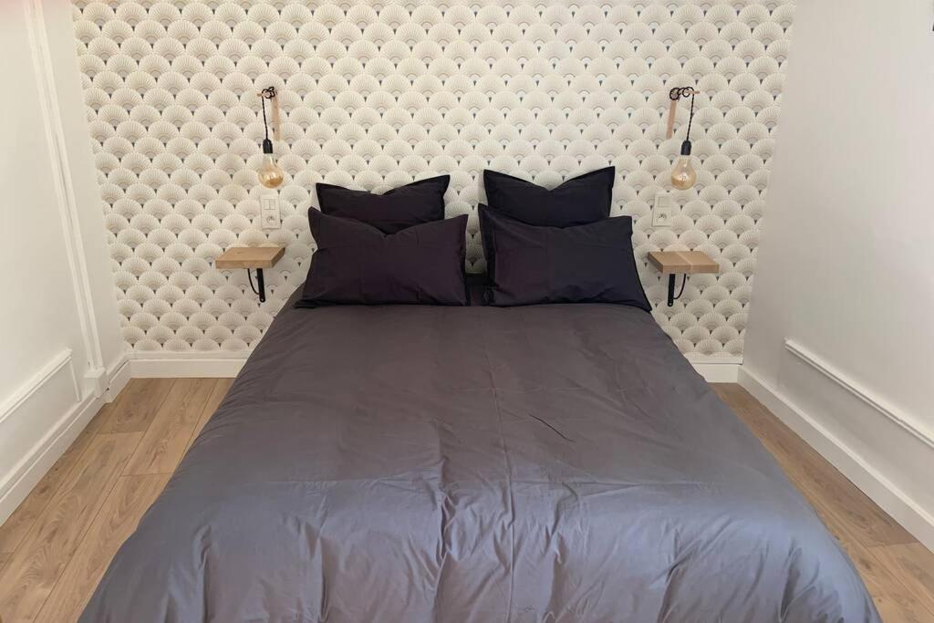 1 cama grande en un dormitorio con 2 lámparas en L’escapade : maison centre-ville avec cour, en Saumur