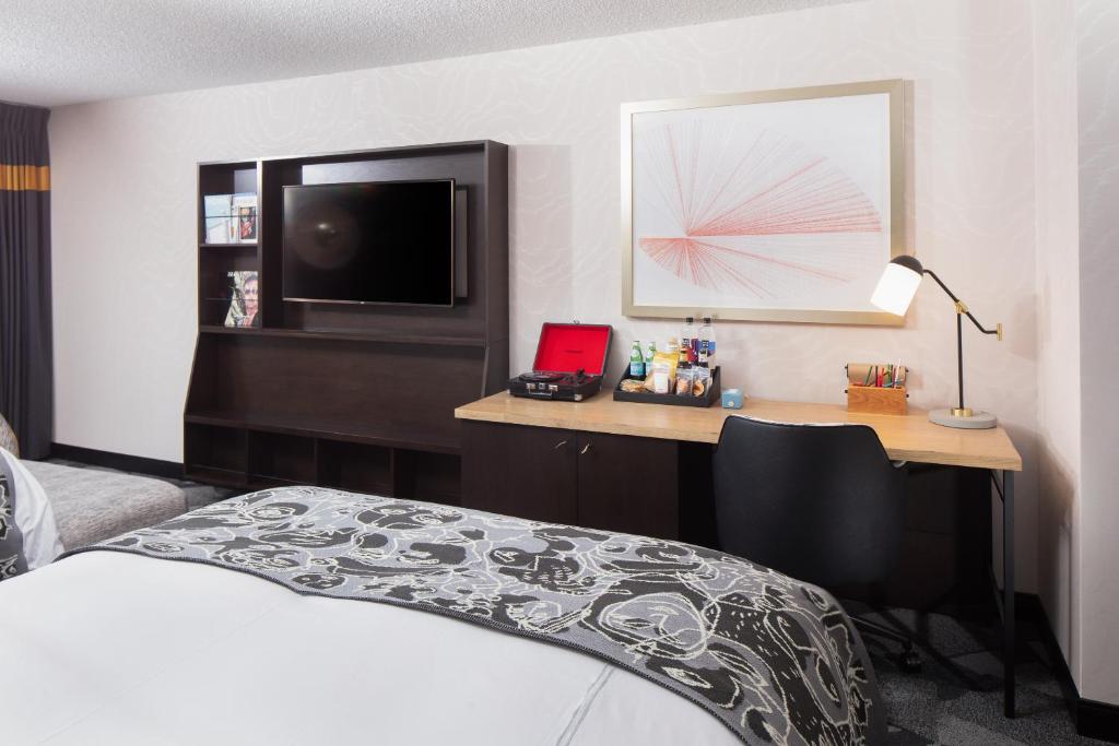 a bedroom with a bed and a desk with a television at Saint Kate - The Arts Hotel in Milwaukee