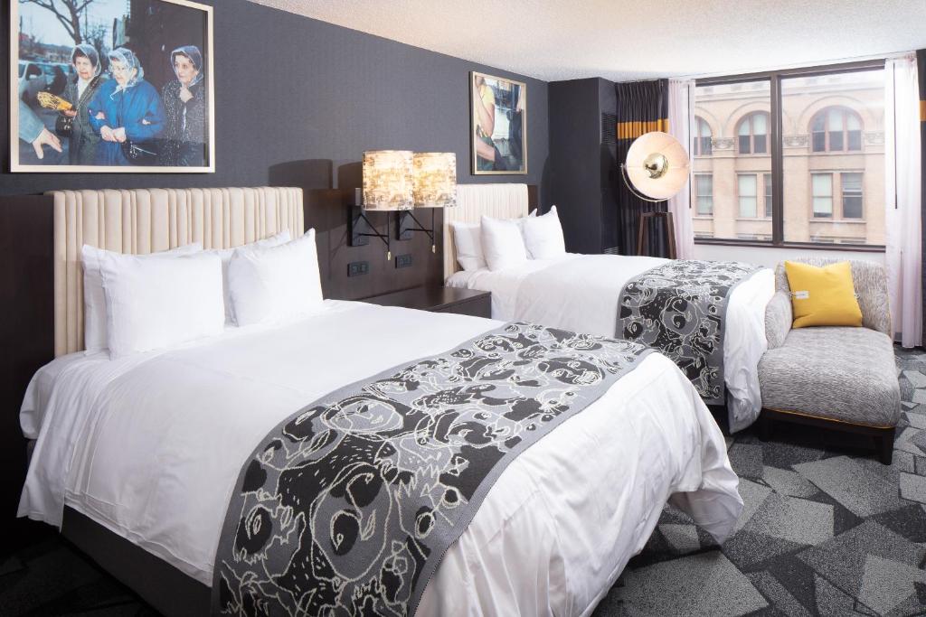a hotel room with two beds and a chair at Saint Kate - The Arts Hotel in Milwaukee