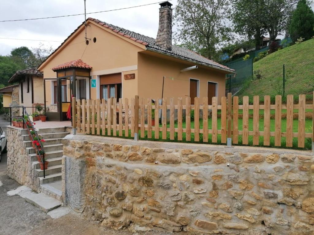 una casa con una valla de madera y una pared de piedra en La casina de la bisa, en Soto de las Dueñas