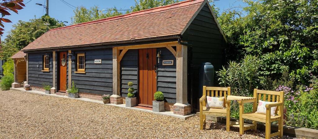 um pequeno barracão com duas cadeiras e uma mesa em The Lodge em Little Clacton