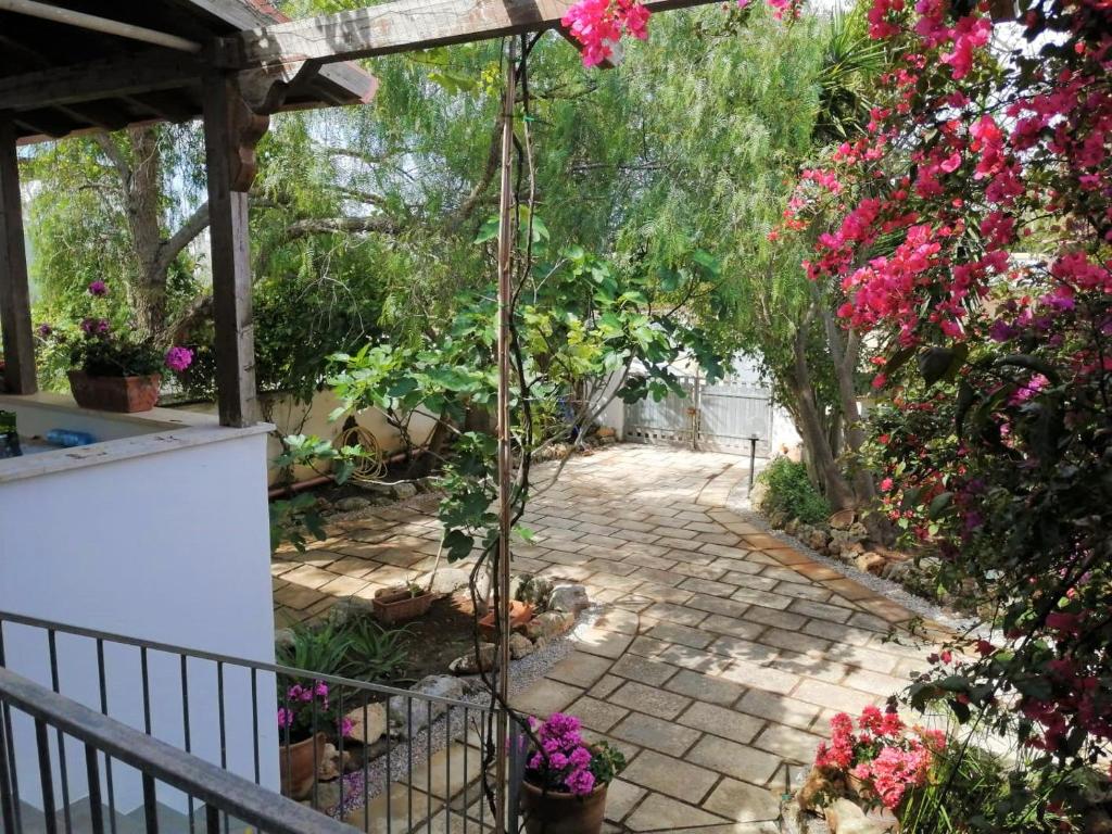 einen Garten mit rosa Blumen und einer Terrasse in der Unterkunft Maresalento Villetta Dante in Marina di Mancaversa