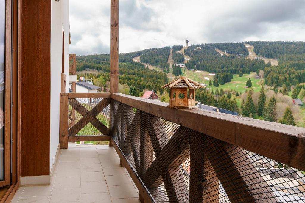 a balcony with a birdhouse and a view of a mountain at Apartmán Švícárek in Loučná pod Klínovcem
