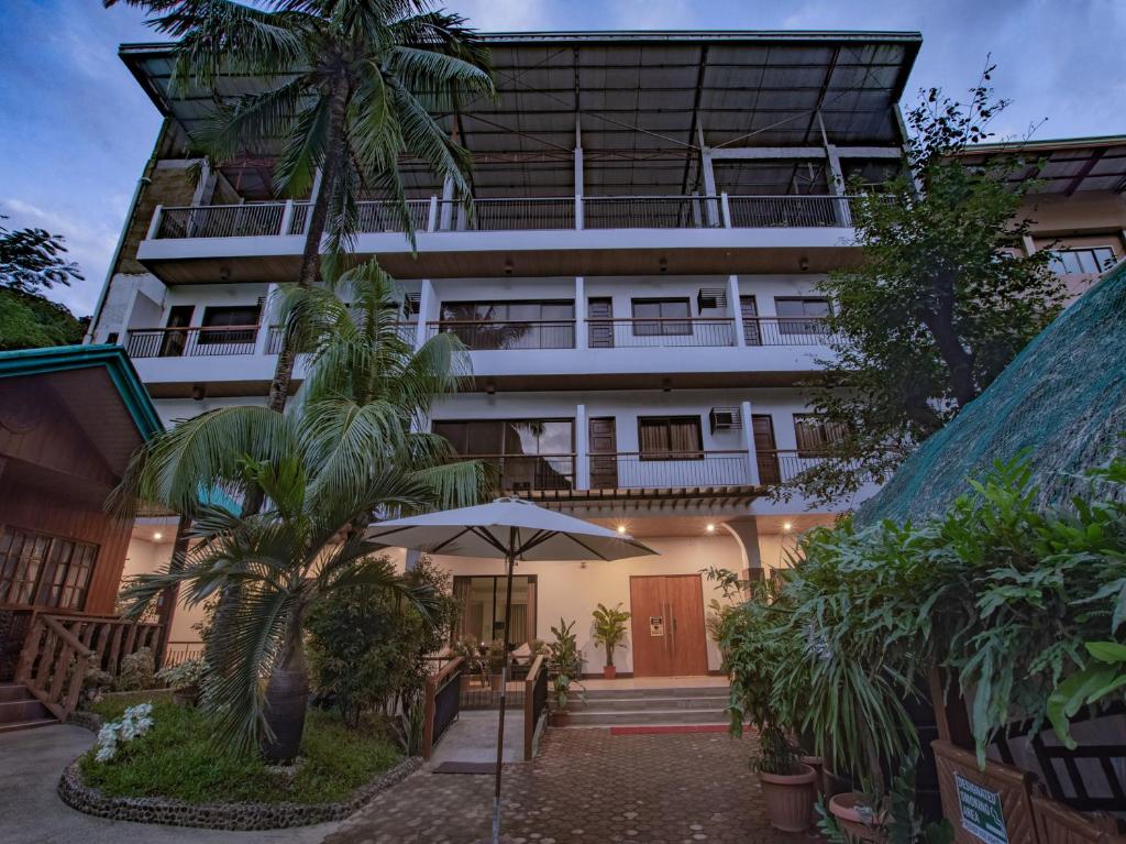 una vista exterior de un hotel con árboles y una sombrilla en Jurias Garden Hotel, en El Nido