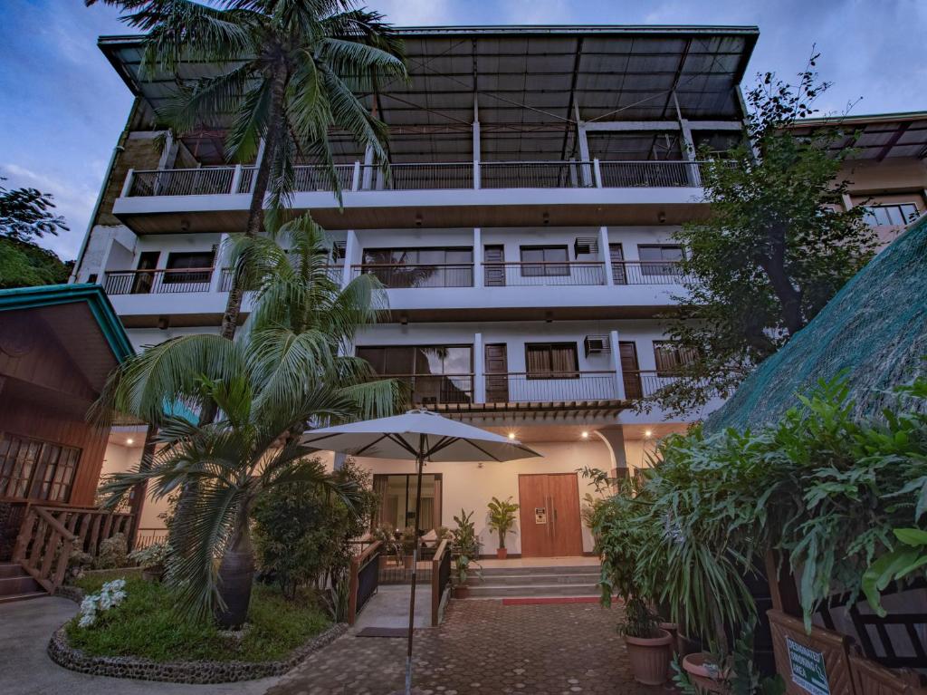 an external view of a hotel with trees and an umbrella at Jurias Garden Hotel in El Nido