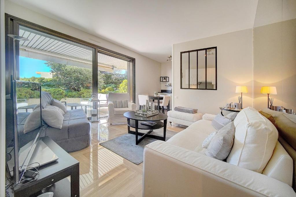 un salon avec des meubles blancs et une grande fenêtre dans l'établissement IMMOGROOM - Close beaches - Terrace with sea view - pool -AC, à Cannes