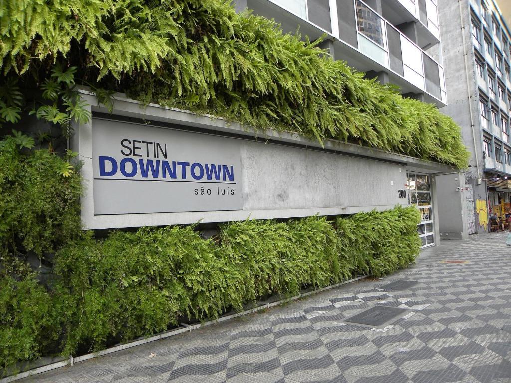 een bord aan de zijkant van een gebouw met planten bij Studio Moderno no centro de SP in Sao Paulo