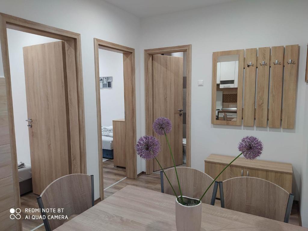 a dining room with a table with purple flowers in a vase at Evelyn Apartman in Hajdúszoboszló