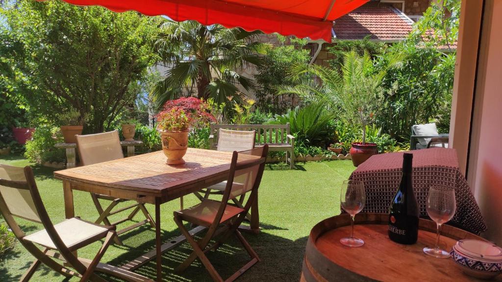 - une table en bois avec une bouteille de vin et 2 chaises dans l'établissement Résidence Chantemerle, à Cannes