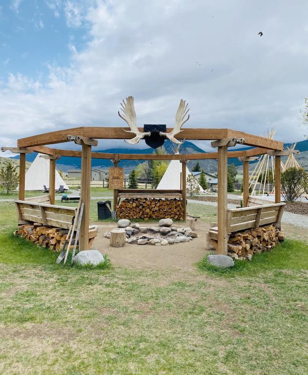a wooden gazebo with a fire pit at Dreamcatcher Tipi Hotel in Gardiner