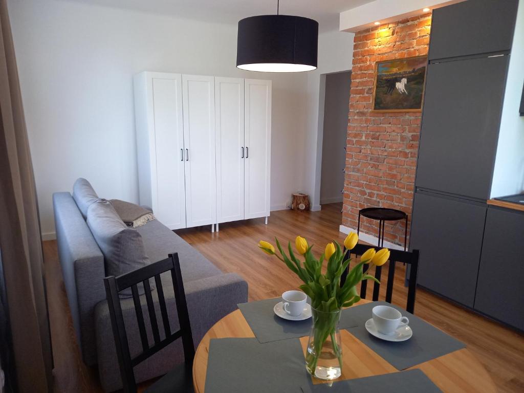 a living room with a couch and a table with yellow flowers at Koszalin-Old Town Apartment in Koszalin
