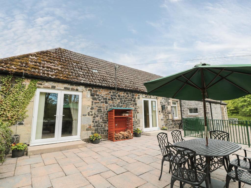 a patio with a table and chairs and an umbrella at Gardener's Cottage in Belford