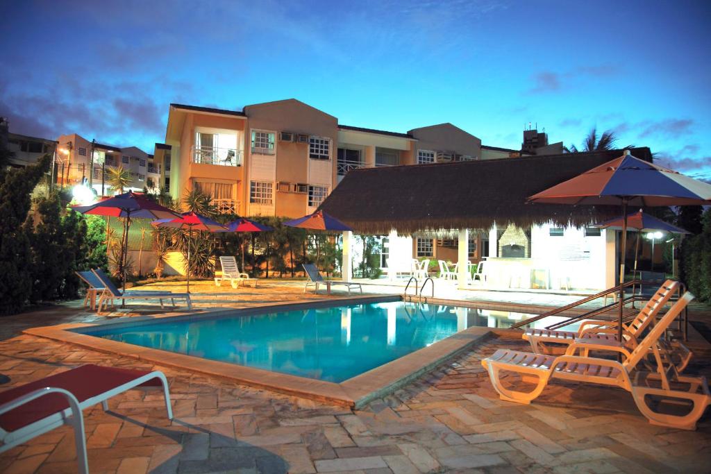 una piscina con sedie e ombrelloni in un resort di Residence Village a Natal