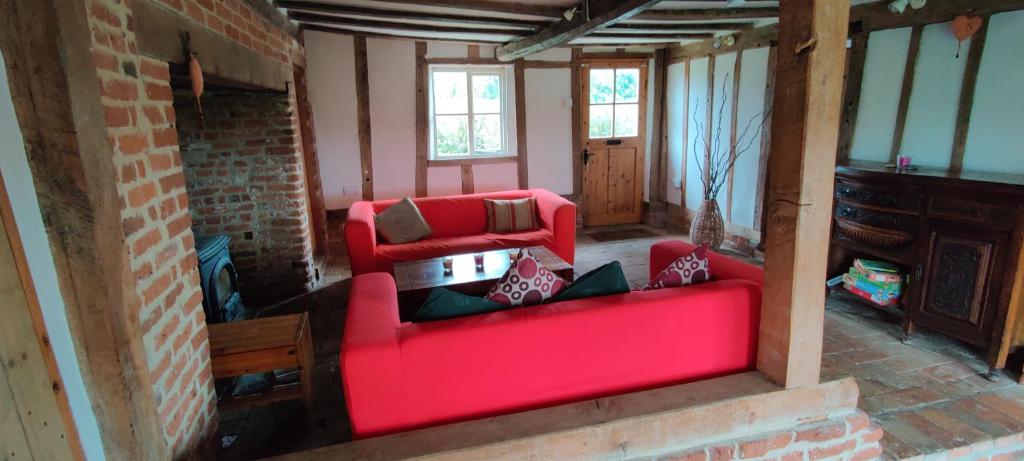 a living room with a red couch and a fireplace at Burnt House Cottage in Barking
